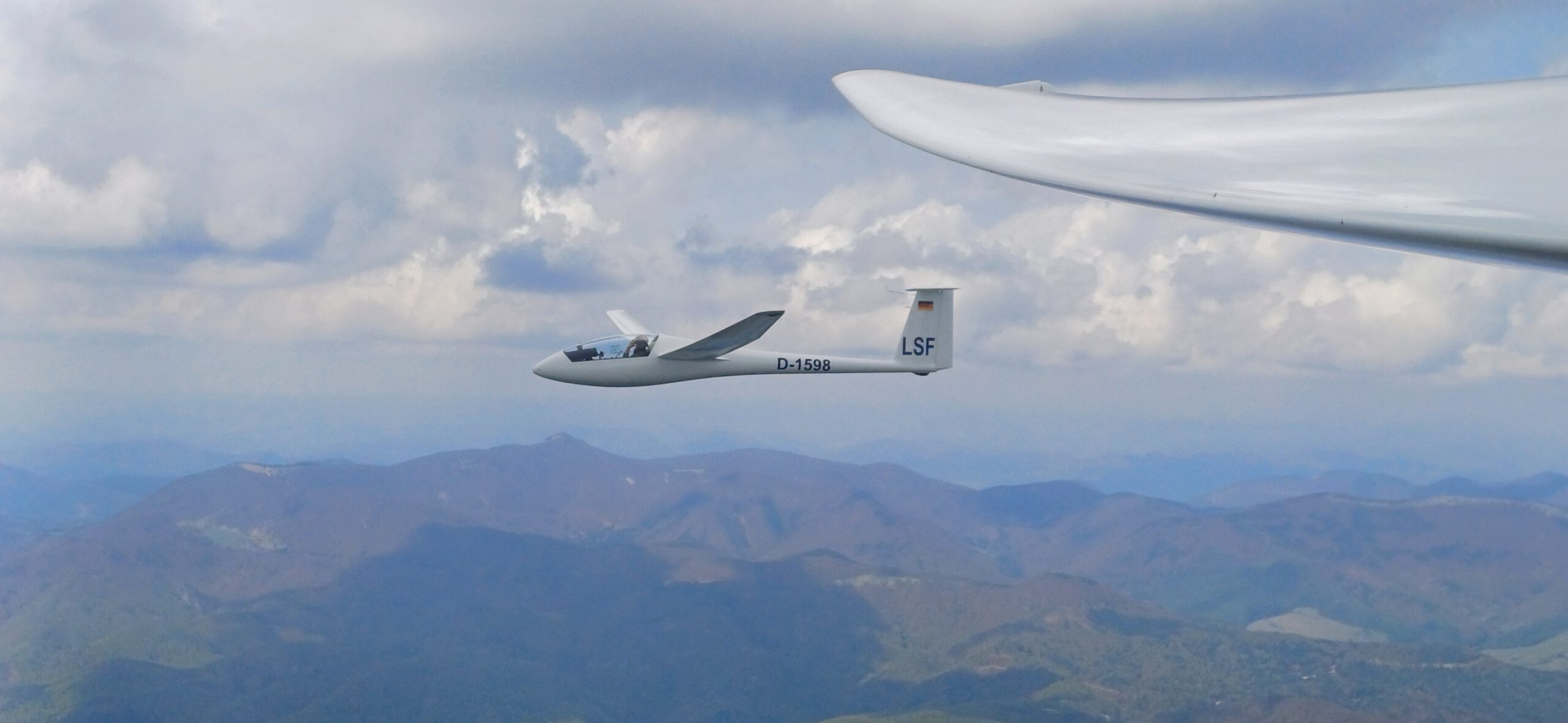 LSF D-1598 beim Fliegen vor dem Klak. Man sieht das Segelflugzeug mit Pilot fliegend neben einem anderen, welches das Foto aufnimmt.